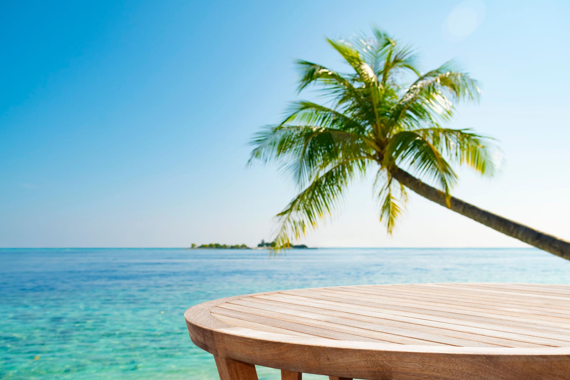 Round wooden table for product montage with tropical sea landscape of palm and island away