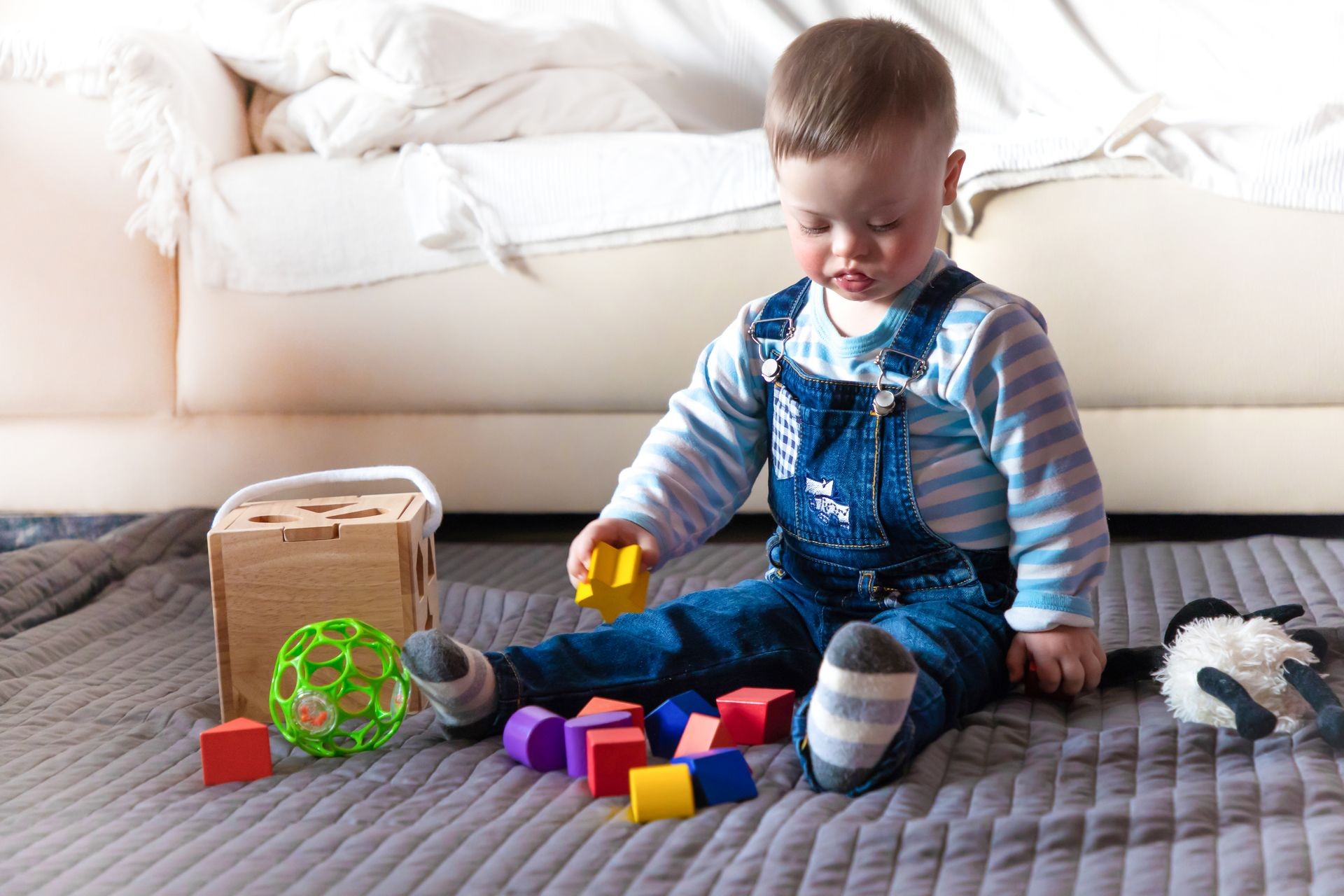 Portrait of cute baby boy with Down syndrome playing in home living room