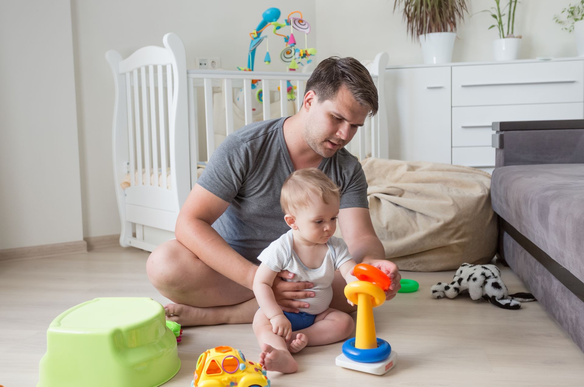 Father sitting on floor with his baby and playing with toys